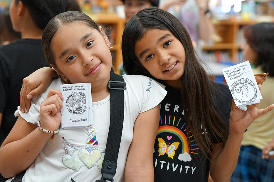 Two girls hold up their mini zines