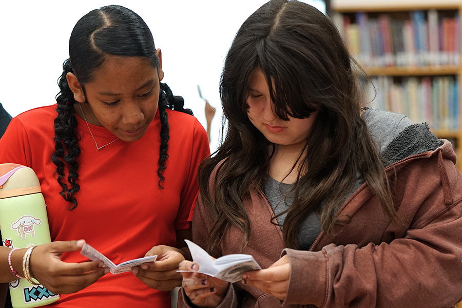 Two girls look through a mini zine