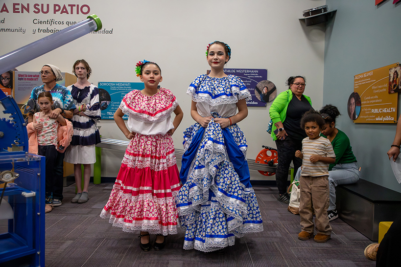 Two girls stand next to each other, in their colorful folklorico dresses