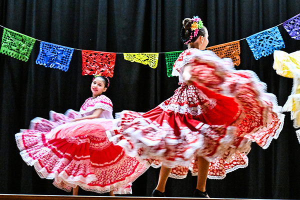 Two girls perform a folklorico dance in red and white dresses