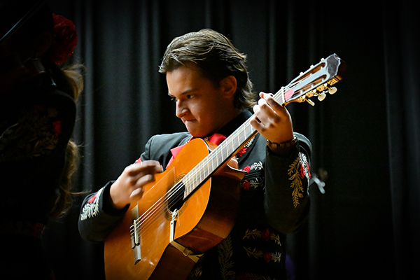 A teen boy focuses as he plays guitar